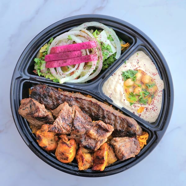 A Don Kabob platter with grilled meats, rice, salad with pickled turnips, and hummus with chickpeas.