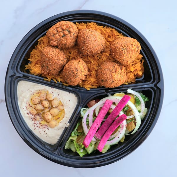 A Don Kabob falafel platter with rice, hummus, and salad in a black to-go container.