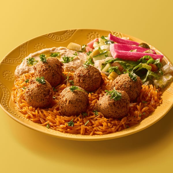 Falafel, rice, hummus, salad, and pickled vegetables on a yellow plate.